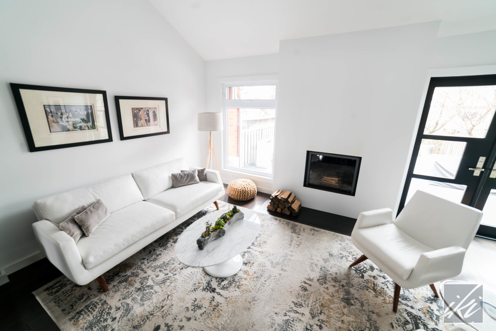 This is an example of a mid-sized modern formal open concept living room in Toronto with white walls, dark hardwood floors, a standard fireplace, a plaster fireplace surround, no tv and black floor.