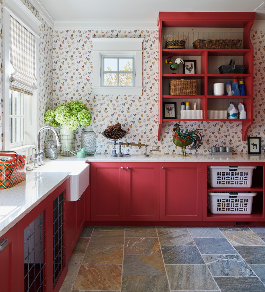 Example of a country l-shaped slate floor, multicolored floor and wallpaper utility room design in Other with a farmhouse sink, recessed-panel cabinets, red cabinets, granite countertops, multicolored walls, a concealed washer/dryer and white countertops