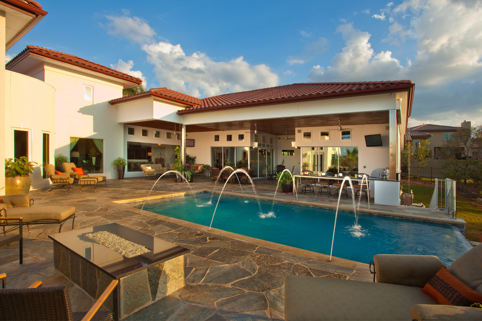Mid-sized mountain style backyard stone and rectangular infinity pool photo in Austin
