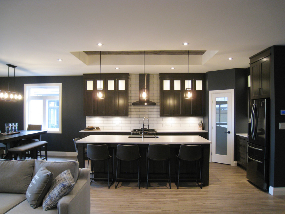 Transitional l-shaped open concept kitchen photo in Toronto with shaker cabinets, dark wood cabinets, quartz countertops, white backsplash, ceramic backsplash, black appliances, an island and white countertops