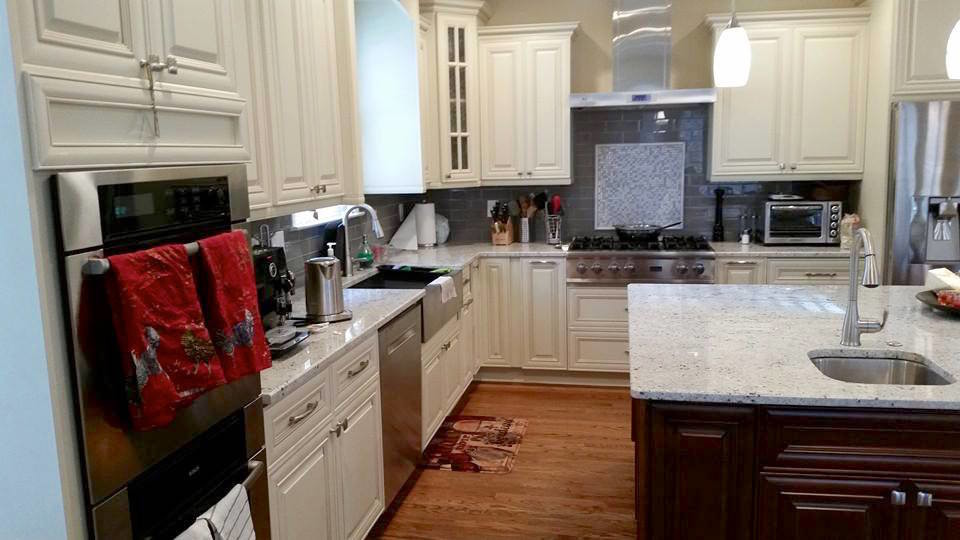 Eat-in kitchen - large transitional l-shaped dark wood floor and brown floor eat-in kitchen idea in Miami with a farmhouse sink, raised-panel cabinets, white cabinets, gray backsplash, subway tile backsplash, stainless steel appliances and an island