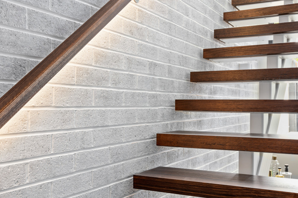 Inspiration for a mid-sized contemporary wood straight staircase in Melbourne with open risers and brick walls.
