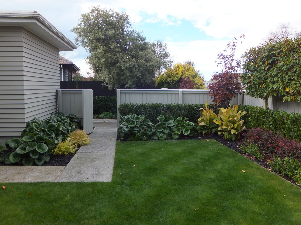 Photo of a mid-sized traditional front yard partial sun formal garden for spring in Christchurch with a garden path and concrete pavers.
