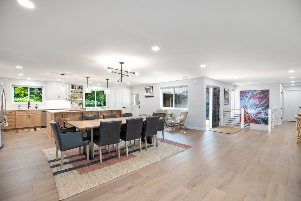Photo of an expansive modern kitchen/dining combo in Portland with white walls, vinyl floors, a wood stove, a metal fireplace surround and beige floor.