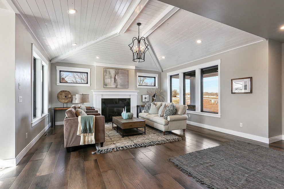 Large traditional open concept living room in Milwaukee with grey walls, medium hardwood floors, a standard fireplace and brown floor.