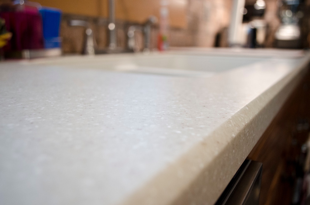 Example of a mid-sized transitional l-shaped vinyl floor eat-in kitchen design in Chicago with an integrated sink, recessed-panel cabinets, dark wood cabinets, solid surface countertops, multicolored backsplash, porcelain backsplash, stainless steel appliances and an island