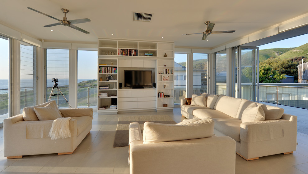 Photo of an expansive beach style open concept family room in Adelaide with white walls, ceramic floors, a corner fireplace, a stone fireplace surround and a freestanding tv.