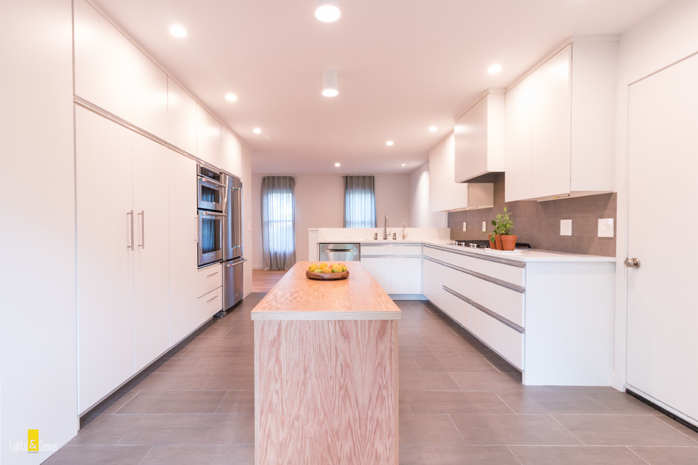 Inspiration for a large modern l-shaped open plan kitchen in Cleveland with a single-bowl sink, flat-panel cabinets, white cabinets, wood benchtops, grey splashback, ceramic splashback, stainless steel appliances, porcelain floors and with island.