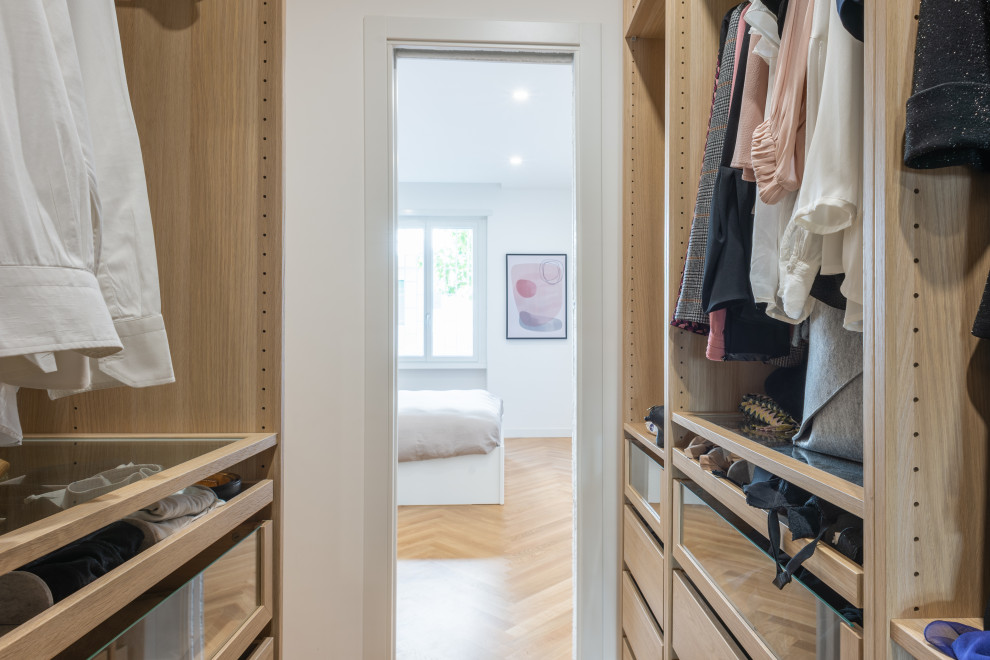Foto de armario vestidor unisex contemporáneo de tamaño medio con armarios abiertos y suelo de madera clara