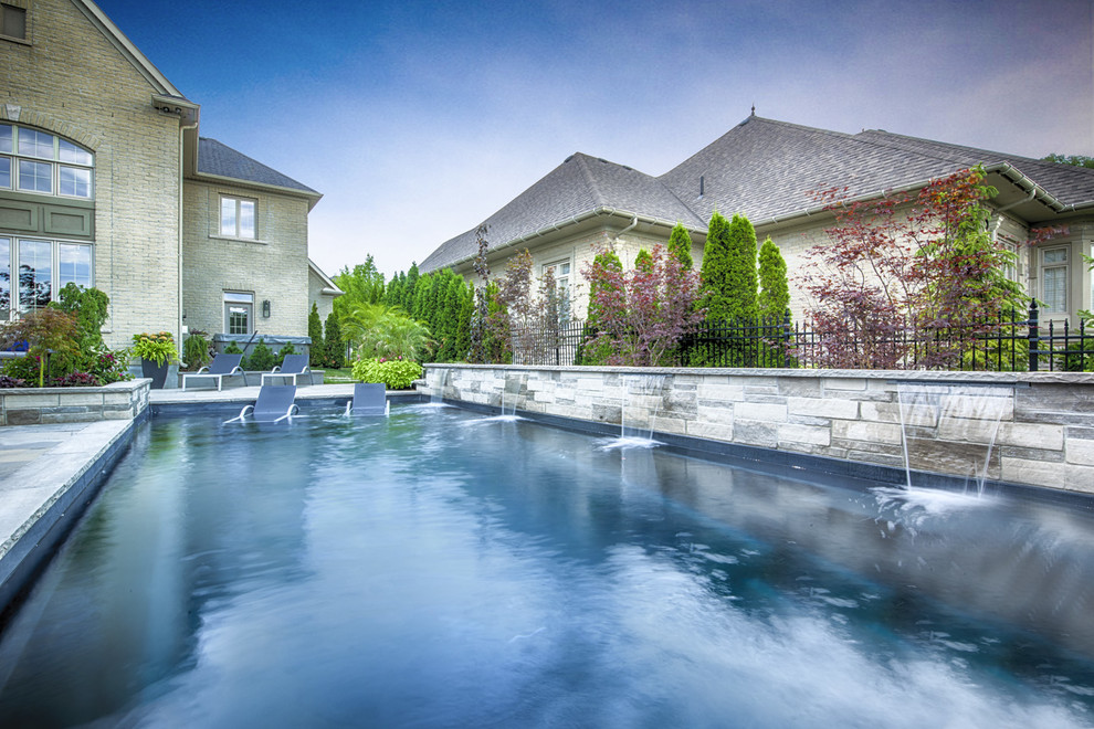 Mid-sized contemporary backyard rectangular pool in Toronto with natural stone pavers.