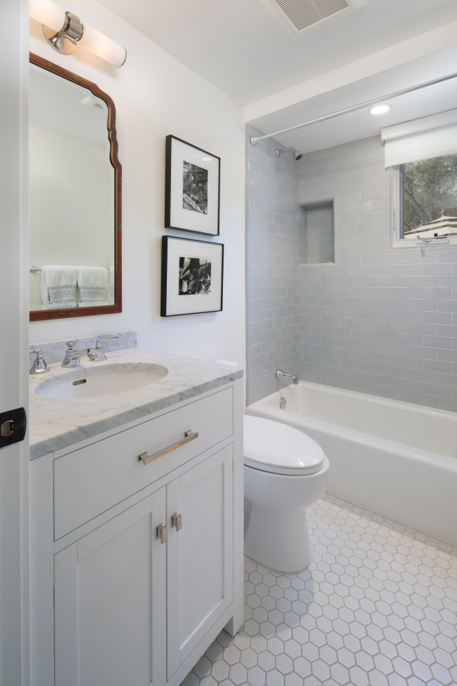 Traditional bathroom in Santa Barbara with white cabinets, a shower/bath combination, a one-piece toilet, grey tiles, metro tiles, white walls, porcelain flooring, marble worktops, white floors, a shower curtain, white worktops, an enclosed toilet, a single sink, a built in vanity unit, shaker cabinets and an alcove bath.