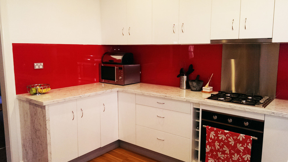 Mid-sized modern kitchen pantry in Sydney with a single-bowl sink, white cabinets, laminate benchtops, red splashback, stainless steel appliances, laminate floors and no island.