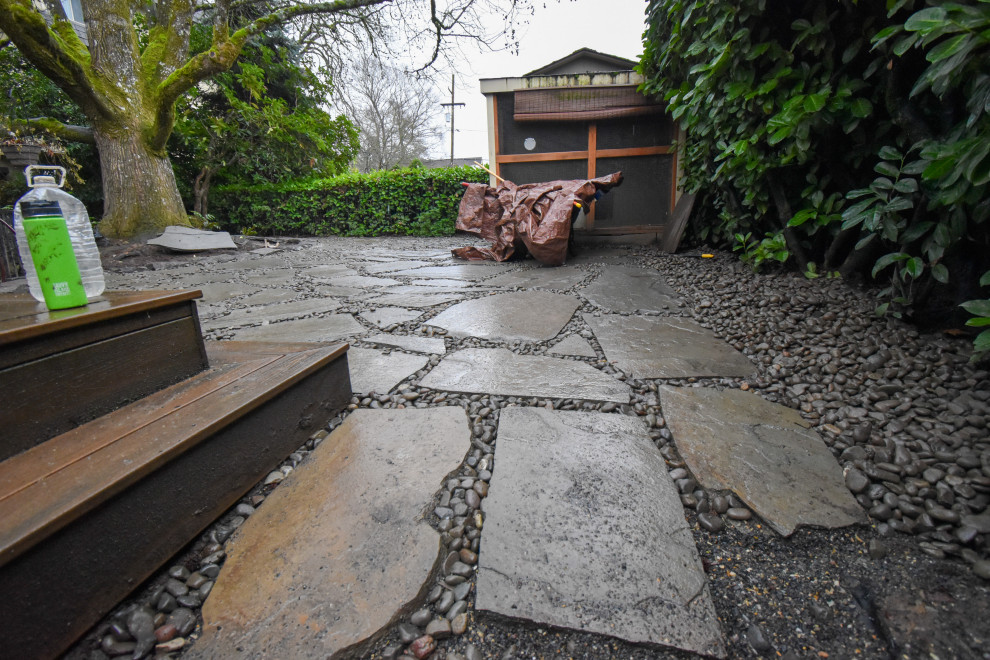 Photo of a large backyard shaded garden in Portland with with rock feature and natural stone pavers.