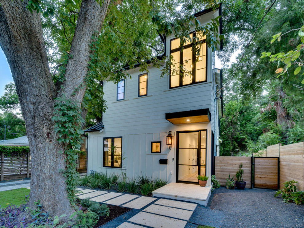 Mittelgroßes, Zweistöckiges Country Einfamilienhaus mit Glasfassade, weißer Fassadenfarbe, Blechdach, schwarzem Dach und Wandpaneelen in Austin