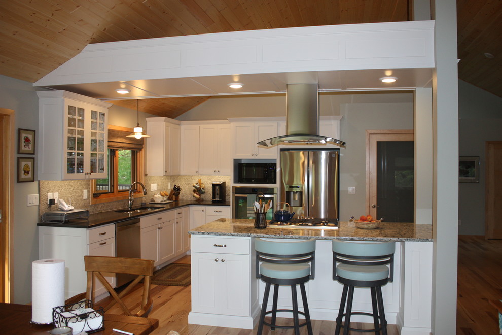 Inspiration for a large transitional l-shaped medium tone wood floor open concept kitchen remodel with a triple-bowl sink, recessed-panel cabinets, white cabinets, solid surface countertops, multicolored backsplash, mosaic tile backsplash, stainless steel appliances and an island