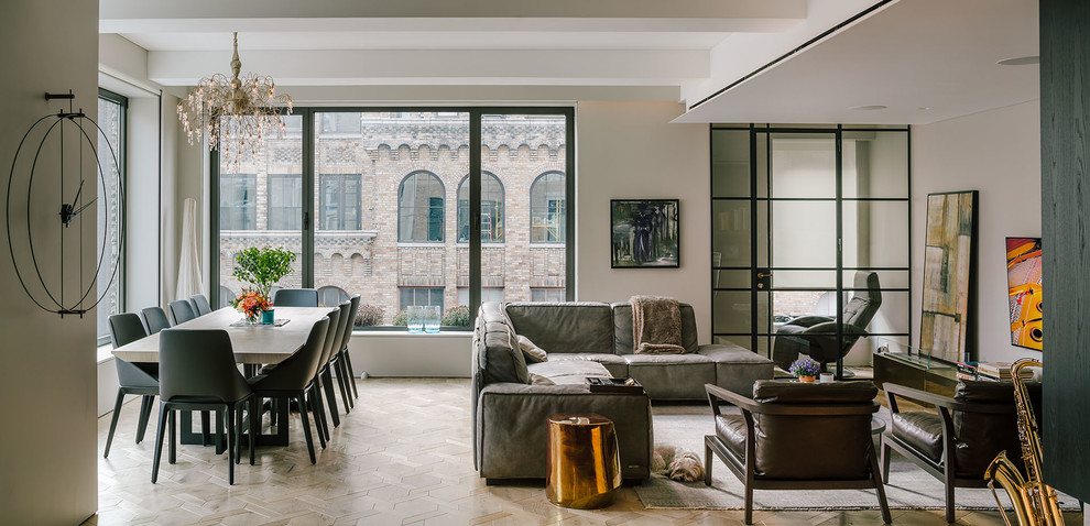 This is an example of a large contemporary formal open concept living room in New York with light hardwood floors, beige floor, grey walls, no fireplace and a wall-mounted tv.