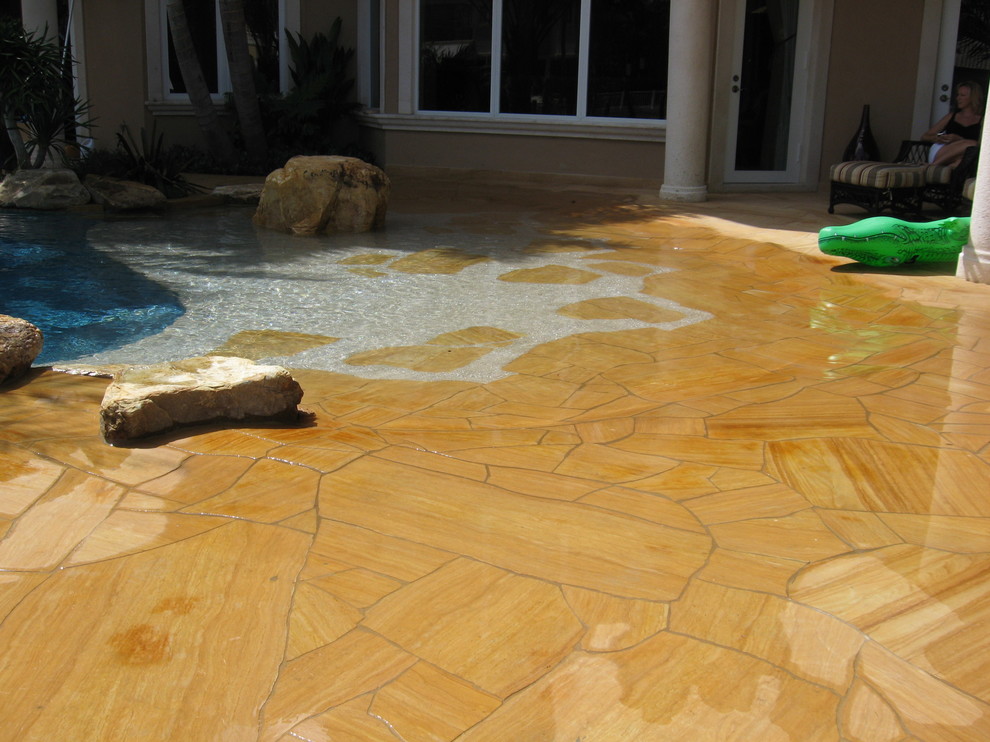 Design ideas for a tropical backyard pool in Miami with a water feature and natural stone pavers.
