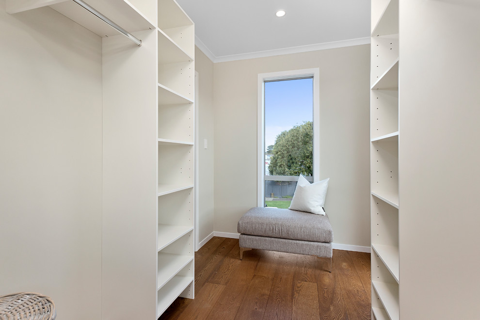 Inspiration for a contemporary gender-neutral walk-in wardrobe in Auckland with open cabinets, white cabinets and light hardwood floors.