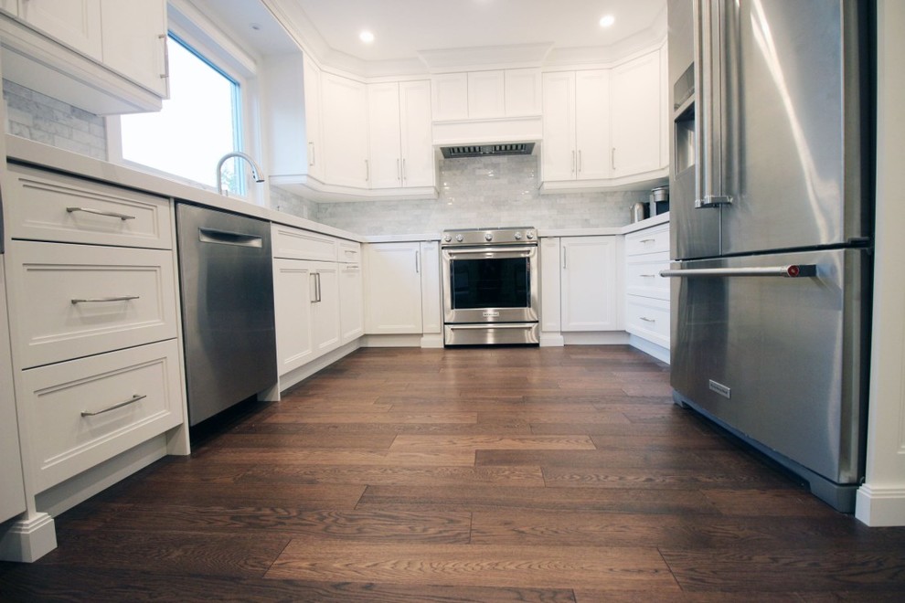 Example of a mid-sized transitional u-shaped medium tone wood floor and brown floor eat-in kitchen design in Toronto with an undermount sink, shaker cabinets, white cabinets, quartzite countertops, white backsplash, ceramic backsplash, stainless steel appliances, an island and white countertops