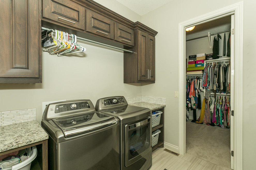Design ideas for a mid-sized transitional galley utility room in Wichita with an undermount sink, raised-panel cabinets, dark wood cabinets, granite benchtops, grey walls and a side-by-side washer and dryer.