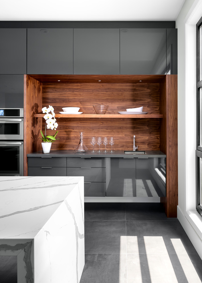 This is an example of a large contemporary single-wall eat-in kitchen in Other with an undermount sink, flat-panel cabinets, grey cabinets, quartz benchtops, grey splashback, stone slab splashback, stainless steel appliances, porcelain floors, with island and grey floor.