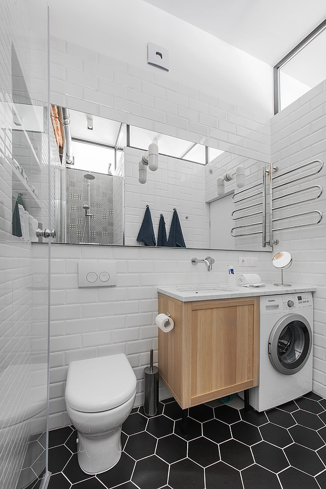 This is an example of a scandinavian 3/4 bathroom in Moscow with shaker cabinets, light wood cabinets, a two-piece toilet, white tile, subway tile, an undermount sink and black floor.