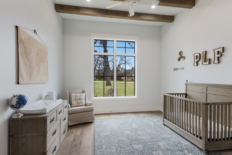 Exemple d'une grande chambre de bébé neutre nature avec poutres apparentes, un mur blanc, parquet clair et un sol beige.