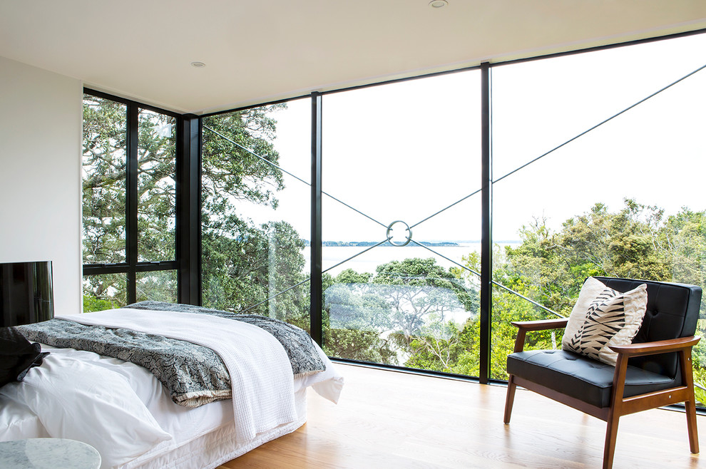 Inspiration for a mid-sized contemporary master bedroom in Auckland with white walls and light hardwood floors.