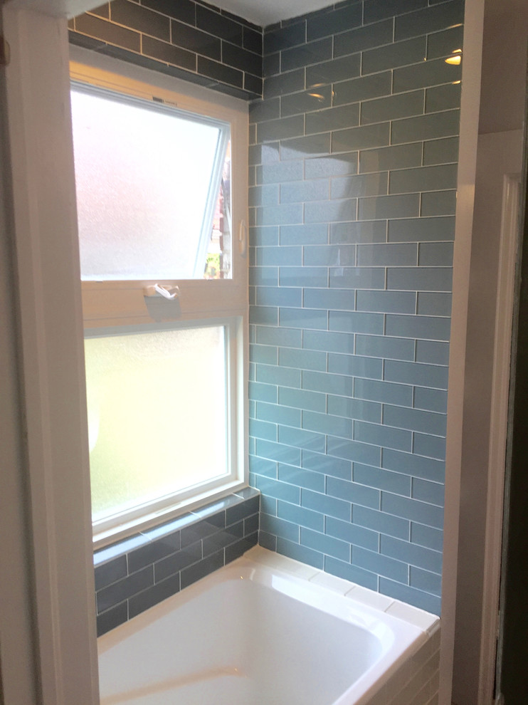 Mid-sized transitional 3/4 blue tile and glass tile dark wood floor and brown floor alcove bathtub photo in Orange County with open cabinets, light wood cabinets, a two-piece toilet, white walls, a drop-in sink and solid surface countertops