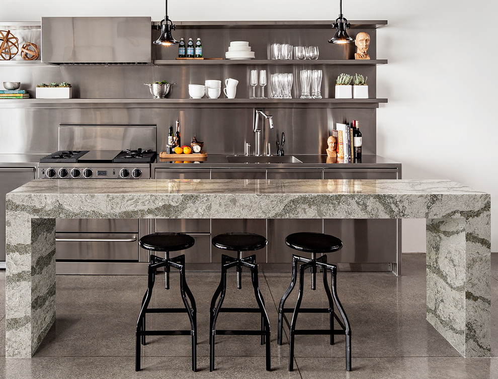 This is an example of a large industrial single-wall eat-in kitchen in New York with stainless steel cabinets, quartz benchtops, metallic splashback, metal splashback, stainless steel appliances, ceramic floors, with island, an integrated sink, open cabinets and grey floor.