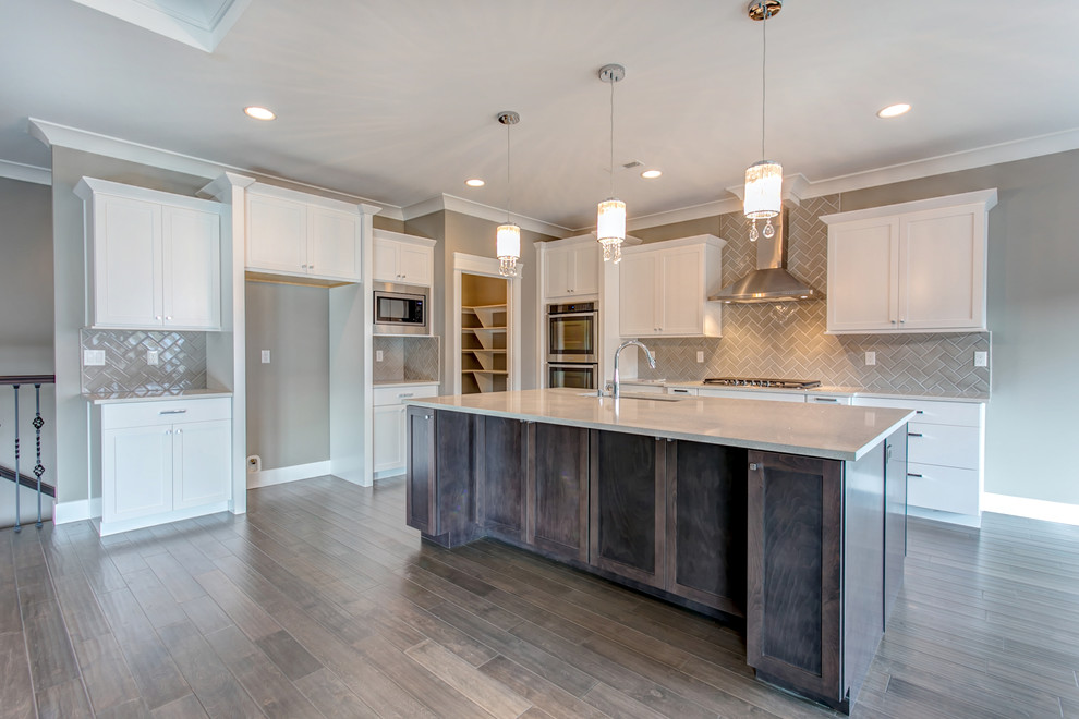 Inspiration for a large transitional l-shaped medium tone wood floor open concept kitchen remodel in Seattle with an undermount sink, shaker cabinets, white cabinets, glass countertops, gray backsplash, glass tile backsplash, stainless steel appliances and an island