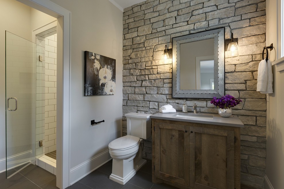 Design ideas for a mid-sized country 3/4 bathroom in Minneapolis with medium wood cabinets, a two-piece toilet, white tile, ceramic tile, grey walls, porcelain floors, shaker cabinets, a corner shower, an undermount sink, engineered quartz benchtops, a hinged shower door, grey floor and grey benchtops.