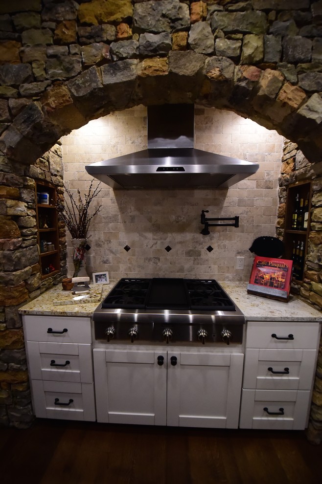 Eat-in kitchen - large rustic u-shaped medium tone wood floor eat-in kitchen idea with an undermount sink, shaker cabinets, white cabinets, granite countertops, beige backsplash, stone tile backsplash, stainless steel appliances and an island