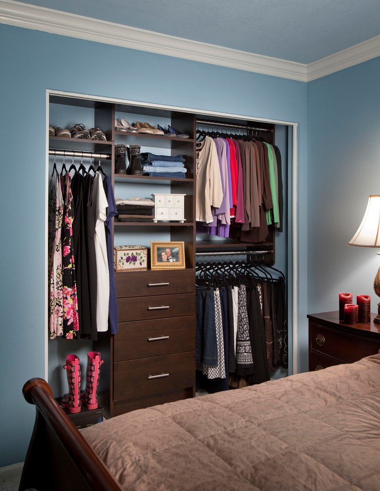 Photo of a small transitional women's built-in wardrobe in Denver with flat-panel cabinets, dark wood cabinets and carpet.