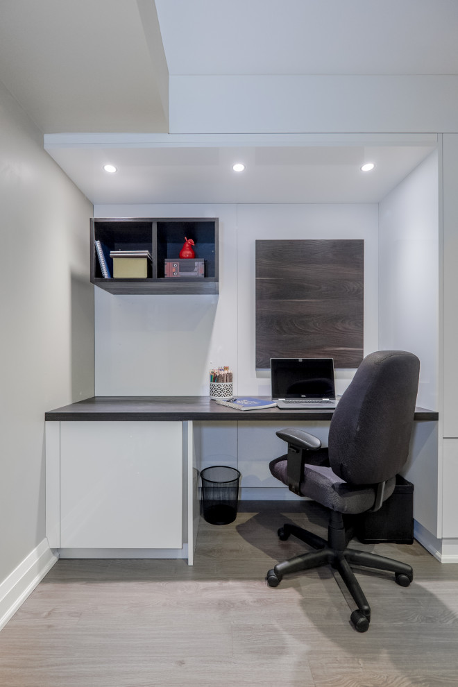 Small modern home office in Toronto with beige walls, laminate floors and brown floor.