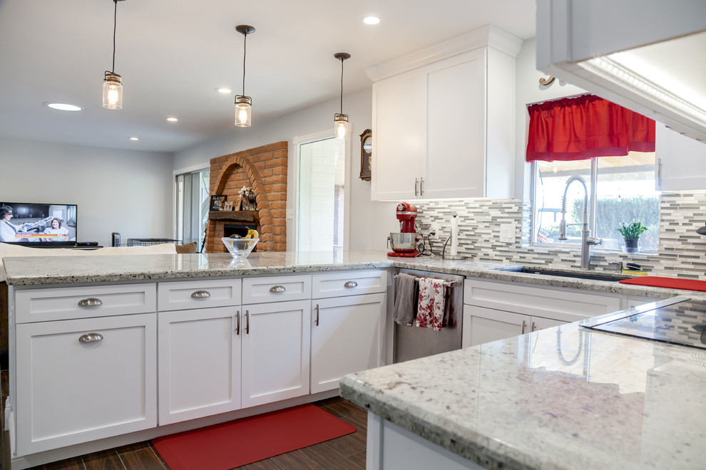 Mid-sized transitional u-shaped laminate floor and brown floor open concept kitchen photo in Phoenix with an undermount sink, recessed-panel cabinets, white cabinets, granite countertops, multicolored backsplash, mosaic tile backsplash and stainless steel appliances