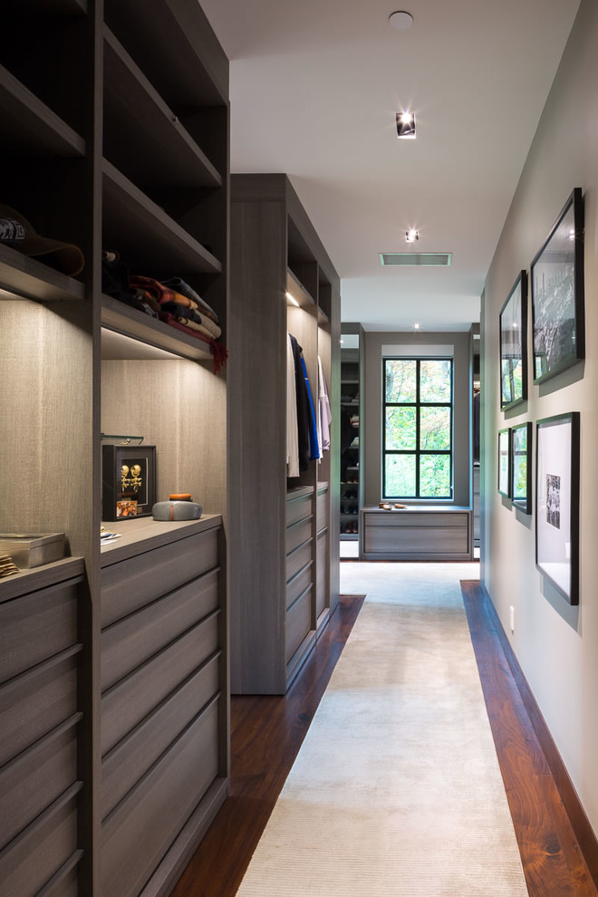 This is an example of an expansive contemporary men's walk-in wardrobe in DC Metro with flat-panel cabinets, medium wood cabinets, carpet and beige floor.