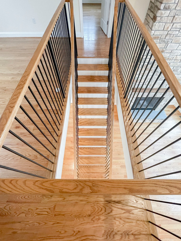 Cette image montre un grand escalier flottant traditionnel avec des marches en bois, des contremarches en bois, un garde-corps en matériaux mixtes et du lambris de bois.