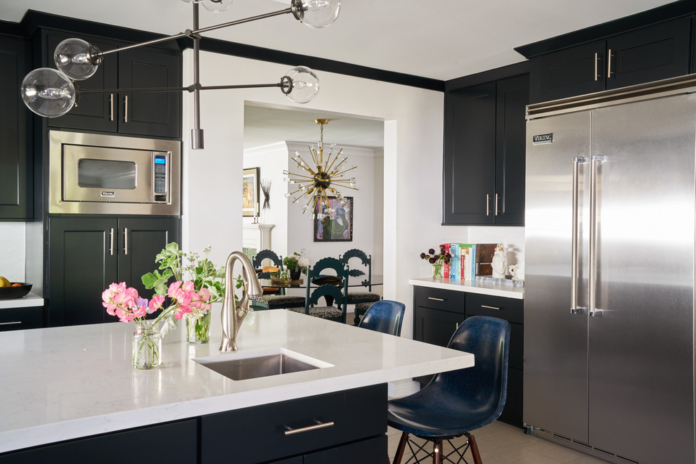 Photo of a mid-sized midcentury open plan kitchen in Charlotte with an undermount sink, shaker cabinets, black cabinets, quartz benchtops, white splashback, stainless steel appliances, porcelain floors, with island, white benchtop and beige floor.