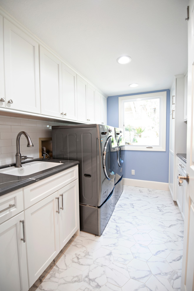 Idéer för en mellanstor klassisk grå parallell tvättstuga enbart för tvätt, med en nedsänkt diskho, luckor med infälld panel, vita skåp, bänkskiva i kvarts, vitt stänkskydd, stänkskydd i tunnelbanekakel, blå väggar, marmorgolv, en tvättmaskin och torktumlare bredvid varandra och vitt golv