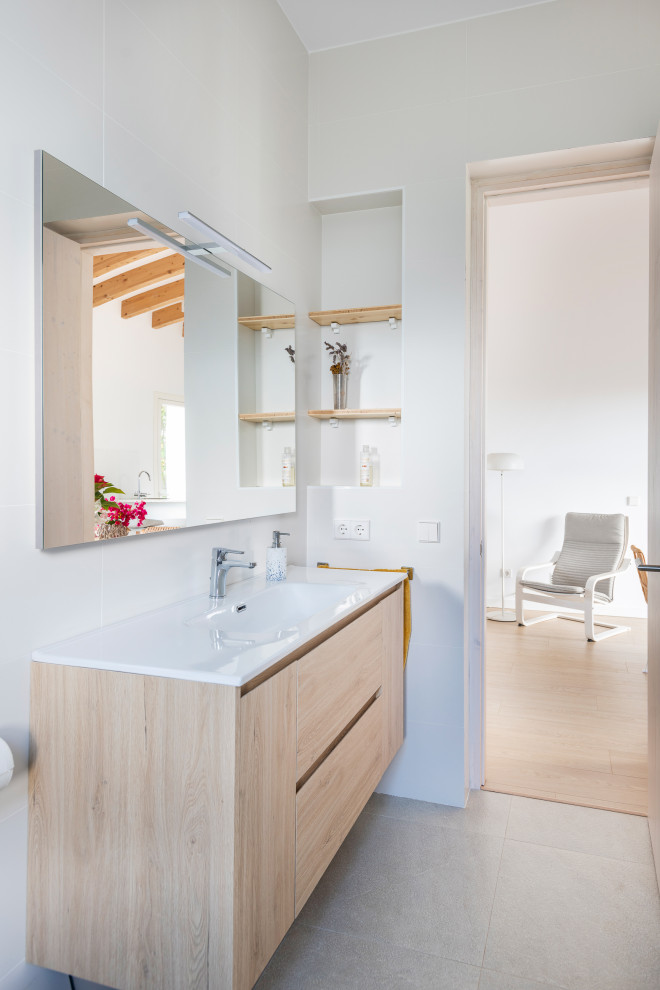 Пример оригинального дизайна: главная, серо-белая ванная комната среднего размера в средиземноморском стиле с фасадами островного типа, белыми фасадами, ванной в нише, унитазом-моноблоком, белой плиткой, белыми стенами, полом из керамической плитки, монолитной раковиной, серым полом, окном, тумбой под одну раковину и подвесной тумбой
