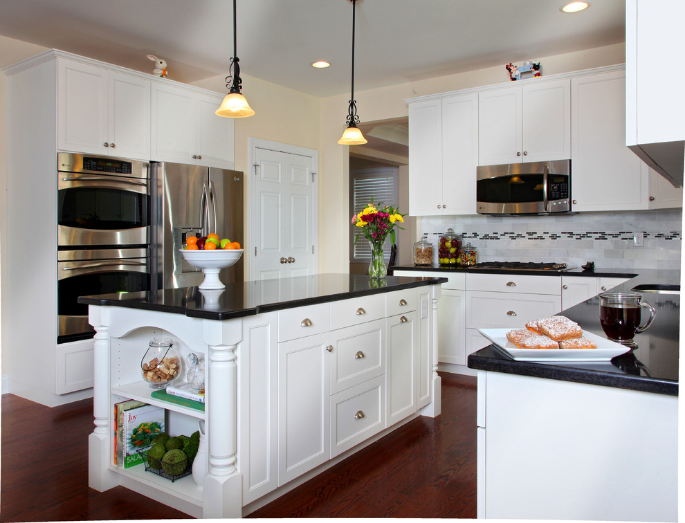 This is an example of a large traditional l-shaped eat-in kitchen in Philadelphia with a single-bowl sink, shaker cabinets, white cabinets, quartzite benchtops, white splashback, ceramic splashback, stainless steel appliances, dark hardwood floors and with island.