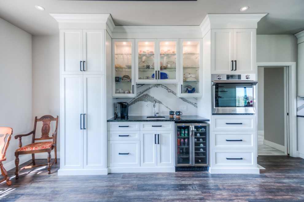 Example of a transitional eat-in kitchen design with shaker cabinets, white cabinets, stainless steel appliances and an island