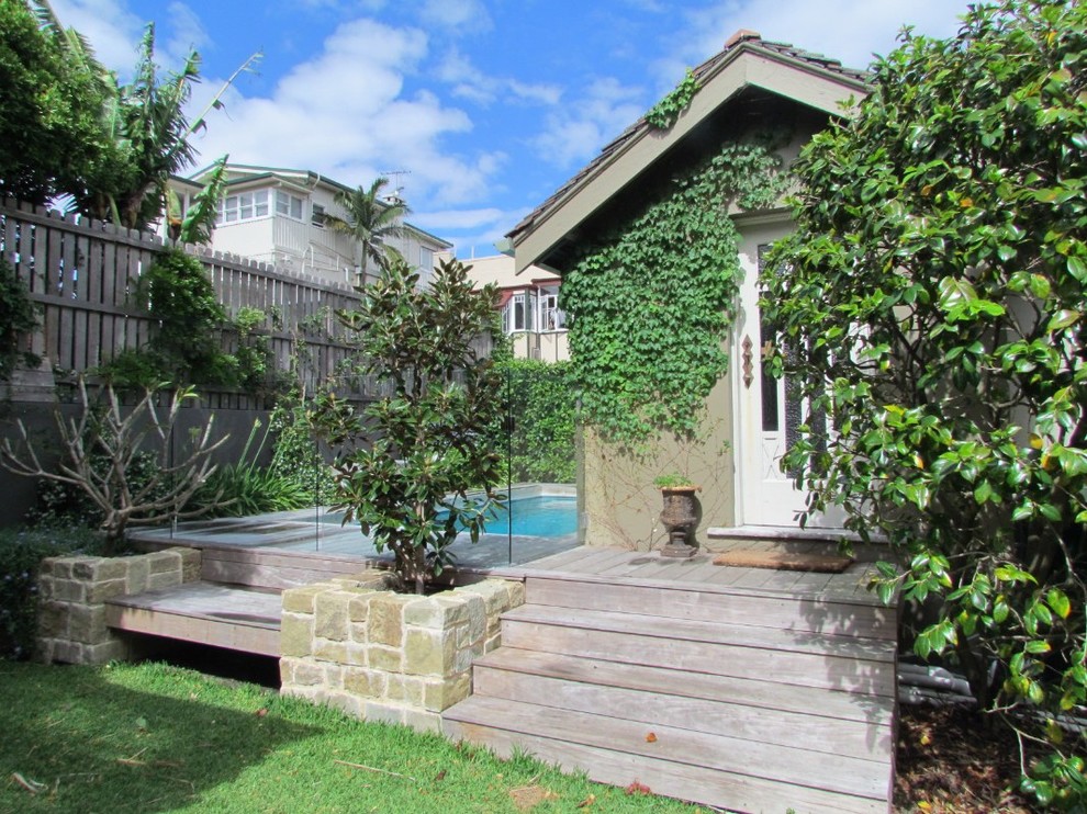 This is an example of a small arts and crafts backyard rectangular pool in Sydney with a pool house and decking.