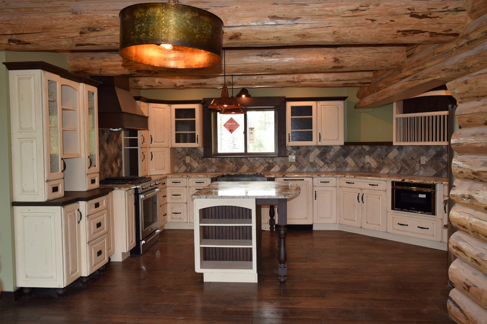 Eat-in kitchen - rustic u-shaped dark wood floor eat-in kitchen idea with a farmhouse sink, raised-panel cabinets, white cabinets, granite countertops, beige backsplash, stone tile backsplash, stainless steel appliances and an island
