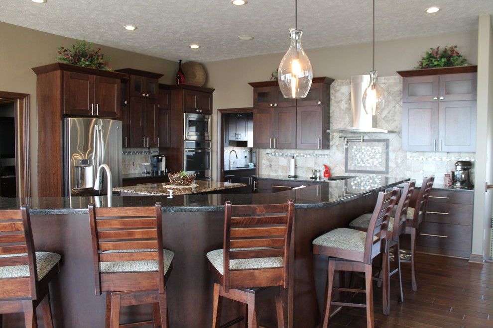 Inspiration for a large transitional single-wall dark wood floor and brown floor open concept kitchen remodel with an undermount sink, dark wood cabinets, granite countertops, beige backsplash, stainless steel appliances, beige walls, two islands, shaker cabinets and stone tile backsplash