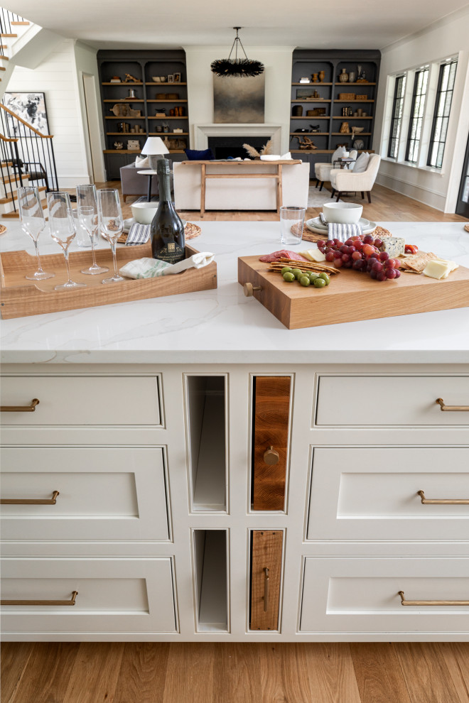 Inspiration for a transitional kitchen in Charlotte with a farmhouse sink, beaded inset cabinets, white cabinets, quartz benchtops, white splashback, engineered quartz splashback, coloured appliances, light hardwood floors, with island, brown floor and white benchtop.