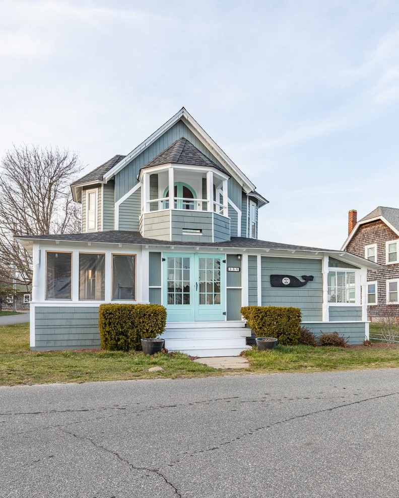 This is an example of a beach style two-storey blue house exterior in Boston with wood siding, a hip roof and a shingle roof.