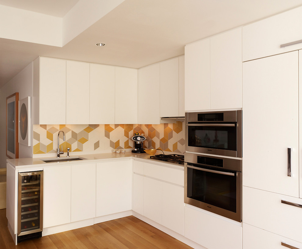 Design ideas for a mid-sized contemporary l-shaped open plan kitchen in New York with an undermount sink, flat-panel cabinets, white cabinets, quartz benchtops, stainless steel appliances, light hardwood floors, no island, ceramic splashback and multi-coloured splashback.
