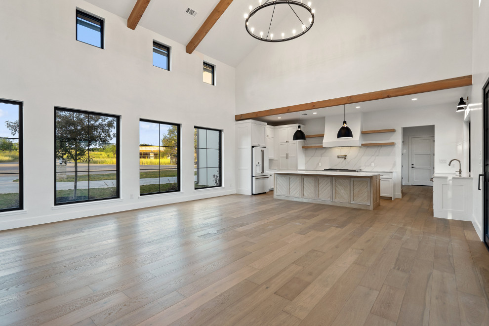 Imagen de salón abierto de estilo de casa de campo con paredes blancas, suelo de madera clara, marco de chimenea de ladrillo y vigas vistas